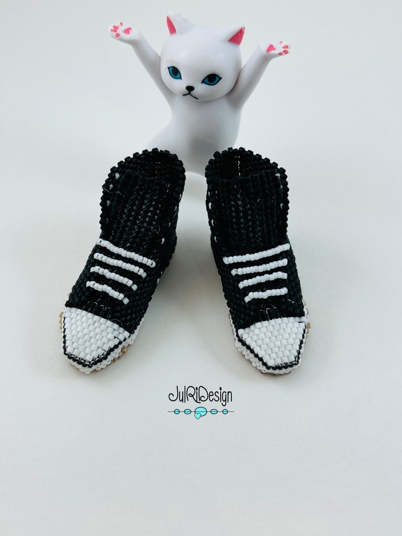 Peut inclure: Une paire de baskets en perles noires et blanches avec des lacets blancs. Les baskets sont assez petites pour s'adapter &agrave; une poup&eacute;e ou une figurine.