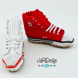 Peut inclure: Une paire de baskets miniatures en perles, une rouge et une blanche, avec des lacets blancs. Les baskets sont d&eacute;taill&eacute;es avec des coutures noires et une semelle blanche. L'image comprend le texte "JulRiDesign".