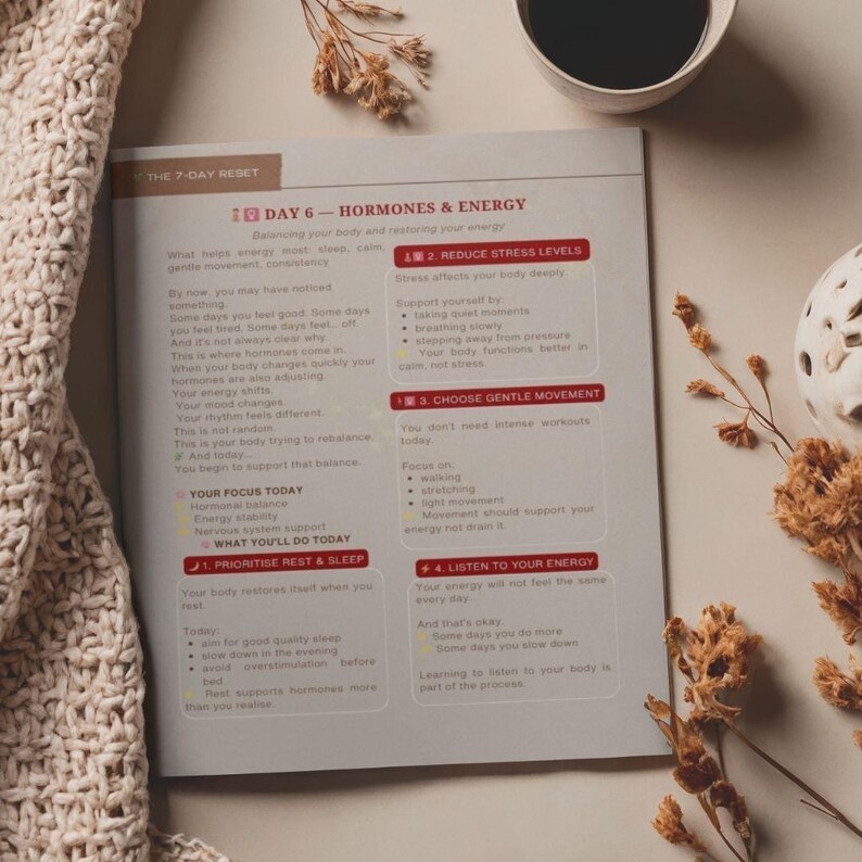 May include: An open book with text about hormones and energy, with a cup of coffee and decorative elements. The book's title is "The 7-Day Reset" and the chapter is "Day 6 - Hormones & Energy". The page includes tips for prioritizing rest and sleep.