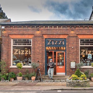 May include: Exterior of a brick building with the name "Zizzi" above the entrance. The windows display the name "Zizzi" in illuminated letters. A person stands in front of the entrance. Plants and flowers are in front of the building.