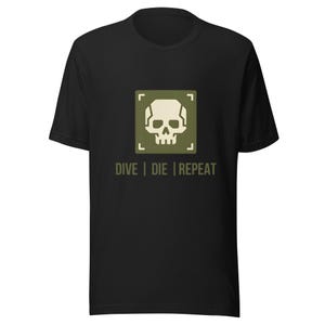 May include: Black t-shirt featuring a skull graphic inside a green square. The text "DIVE | DIE | REPEAT" is below the graphic. The shirt is made of a soft material and has short sleeves.