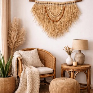 K&ouml;nnte beinhalten: Gem&uuml;tliches Wohnzimmer mit einem Rattanstuhl, einer Strickdecke und einem Wandbehang aus Naturfasern. Ein kleiner Beistelltisch mit Lampe und Vase. Der Raum ist in neutralen Farben gehalten.