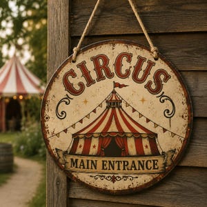 May include: A round, distressed metal sign with a cream background and a red and white striped circus tent illustration. The word CIRCUS is printed in large red letters at the top, and the text MAIN ENTRANCE is on a banner at the bottom.