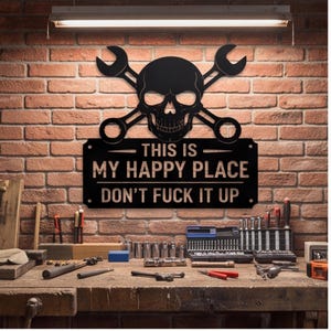 May include: A black metal wall sign featuring a skull centered between two crossed wrenches. The sign includes the text "THIS IS MY HAPPY PLACE" and "DON'T FUCK IT UP" in bold, capitalized lettering, with small circular mounting holes at each corner.