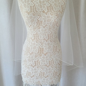 May include: White bridal veil with a delicate floral pattern and a fringe trim, displayed on a white mannequin.