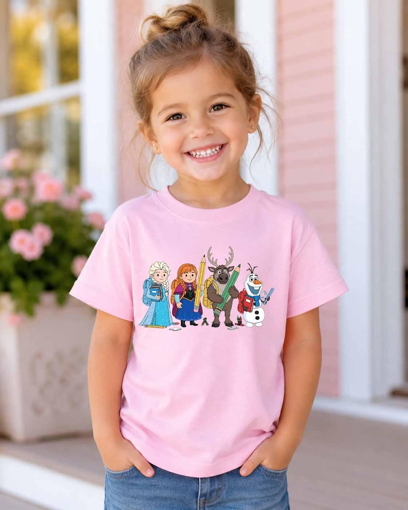 Puede incluir: Una camiseta de manga corta de color rosa claro con un estampado gr&aacute;fico de cuatro personajes animados de Frozen, incluidos Elsa, Anna, Sven y Olaf, cada uno con &uacute;tiles escolares como mochilas, l&aacute;pices y libros en la parte delantera.