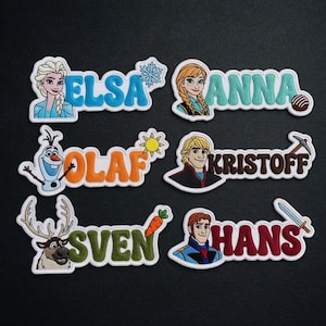 May include: Embroidered patches featuring characters and names from the movie Frozen. The patches include Elsa, Anna, Olaf, Kristoff, Sven, and Hans. Each patch has a white border and colorful details, perfect for decorating clothing or accessories.