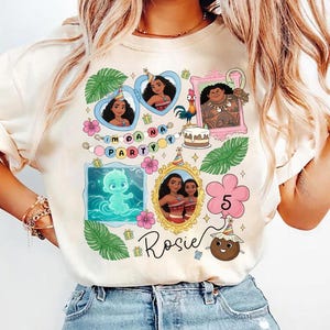 Puede incluir: Una camiseta de color crema con un estampado gr&aacute;fico colorido de personajes de Moana, hojas tropicales, flores de hibisco, un pastel de cumplea&ntilde;os y un globo con el n&uacute;mero 5. El texto "PARTY" y el nombre "Rosie" est&aacute;n impresos en la camiseta.