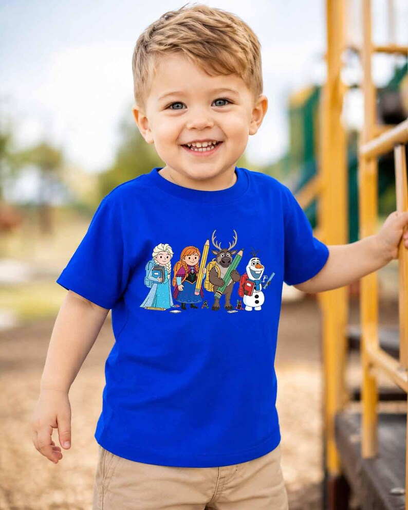 Puede incluir: Una camiseta de manga corta de color azul brillante con un estampado gr&aacute;fico colorido de cuatro personajes animados de la franquicia Frozen, incluidos Elsa, Anna, Sven y Olaf, cada uno sosteniendo &uacute;tiles escolares como l&aacute;pices y libros.