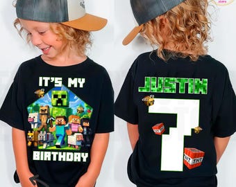 Op de afbeelding: Zwart T-shirt met een Minecraft-verjaardagsontwerp. De voorkant toont de tekst "IT'S MY BIRTHDAY" met Minecraft-personages. De achterkant toont de naam "JUSTIN" en het nummer "7".
