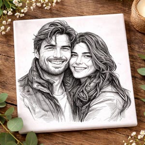 May include: Square ceramic tile featuring a black and white sketch of a smiling couple. The artwork depicts a man and a woman embracing, with detailed shading and a focus on their facial expressions. The tile is set against a wooden background.