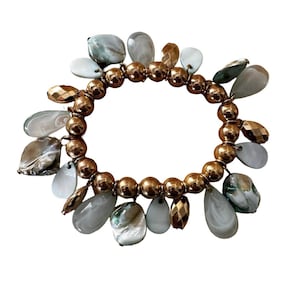 May include: A gold beaded bracelet with multiple white and green shell charms. The bracelet is made of gold-toned metal beads and has a variety of shell charms in different shapes and sizes.