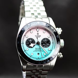 Puede incluir: Un reloj cron&oacute;grafo Tudor de acero inoxidable con una esfera degradada que pasa de blanco en la parte superior a turquesa en la inferior. Cuenta con un bisel taquim&eacute;trico negro, dos subesferas negras, una ventana de fecha a las seis y un brazalete de eslabones met&aacute;licos.
