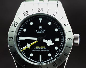 Cronómetro automático Tudor reacondicionado con esfera negra e indicador de fecha.