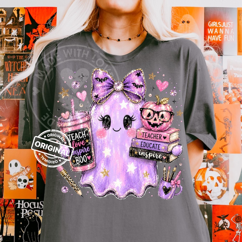 May include: A dark gray t-shirt featuring a graphic of a purple ghost with a large bow, a tumbler with the text "TEACH love inspire BOO", a stack of books labeled "TEACHER EDUCATE inspire", a pumpkin with glasses, and a mug with pencils.