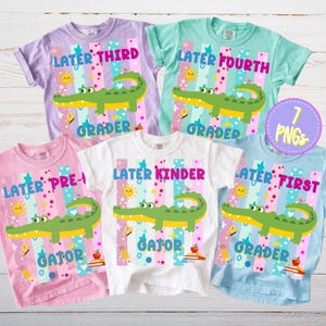 Könnte beinhalten: Fünf farbenfrohe Kinder-T-Shirts mit Schulmotiven. Jedes Shirt zeigt ein Cartoon-Alligator, die Wörter "Later" und eine Klassenstufe sowie das Wort "Gator". Die Shirts sind in verschiedenen Farben wie Rosa, Lila, Weiß, Blau und Grün gehalten.