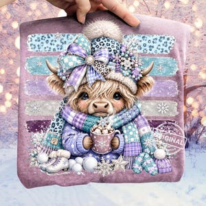 May include: A purple t-shirt featuring a graphic of a fluffy Highland cow wearing a blue and purple leopard print beanie with a large bow, a matching scarf, and white ice skates, holding a mug of hot cocoa with snowflakes and stars.