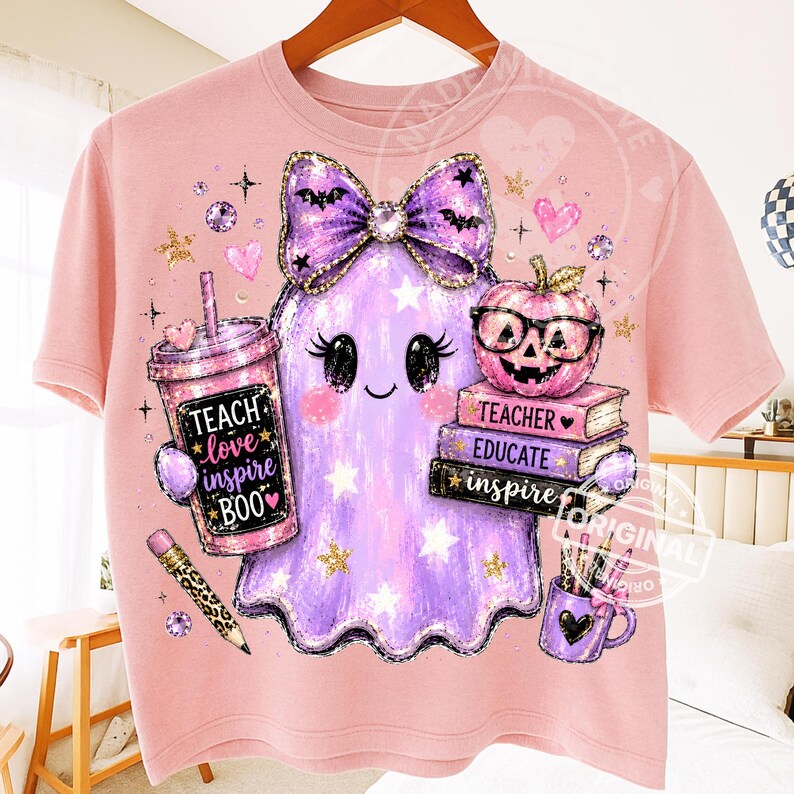 May include: A light pink t-shirt featuring a graphic of a purple ghost wearing a large bow, holding a pink tumbler with the text TEACH LOVE INSPIRE BOO, a stack of books labeled TEACHER EDUCATE INSPIRE, a pencil, and a mug with pens.
