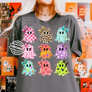 Op de afbeelding: Een donkergrijs t-shirt met een grafische print van negen geesten in een raster. Elke geest heeft een uniek patroon, waaronder ruiten, luipaardprint, strepen, smileys, sterren, bliksemschichten en hartjes, allemaal versierd met strikjes.