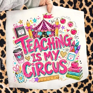 May include: A white decorative pillow with a colorful design. The pillow features the text "TEACHING IS MY CIRCUS" in pink and blue, along with illustrations of a circus tent, pencils, apples, and school supplies.