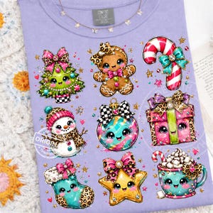 May include: A light purple t-shirt featuring a graphic print of nine festive characters including a decorated Christmas tree, a gingerbread person, a candy cane, a snowman, a bauble, a gift box, a stocking, a star, and a mug of hot cocoa.