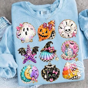 May include: A light blue crewneck sweatshirt featuring a graphic print of nine Halloween-themed seashells and sea creatures, including a ghost shell, a jack-o'-lantern shell, a skull shell, a bat-winged starfish, and a potion bottle shell.