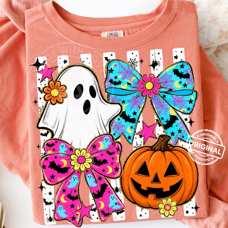以下が含まれることがあります： ハロウィーンをテーマにしたグラフィックが特徴の、コーラル色のスウェットシャツ。白い幽霊、コウモリとクモの巣の2つのカラフルなリボン、ジャック・オー・ランタンのデザイン。シャツの上部には「COMFORT」の文字がプリントされています。