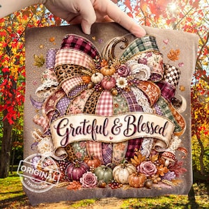 Puede incluir: Un estampado en tela que muestra una calabaza grande decorada con varias cintas estampadas, incluyendo cuadros, leopardo y motivos florales. Una cinta en el centro dice "Grateful & Blessed". Pequeñas calabazas y flores rodean la base del diseño.
