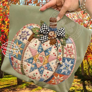 May include: A fabric pumpkin decoration featuring a patchwork quilt design with blue, pink, and yellow star patterns, cherry prints, and floral motifs. It is topped with a brown stem, green fabric leaves, and a black and white checkered bow.