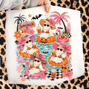 Könnte beinhalten: Ein weißes Strandtuch mit einer skurrilen Illustration von Geistern mit Sonnenbrillen und Hüten, die in einem Pool auf Kürbis-Schwimmkörpern schwimmen. Das Design umfasst Palmen, einen Flamingo-Schwimmer und den Text "Summerween".