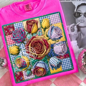 May include: A bright pink t-shirt with a colorful patchwork design featuring fabric roses. The patchwork includes various patterns like gingham and floral prints. The word "ORIGINAL" is stamped on the patchwork. The shirt has a tag that says "Comfort Colors".