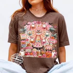 May include: Brown t-shirt featuring a colorful carnival scene with a Ferris wheel, ghosts, pumpkins, and the text "Summerween Vibes." The design includes signs that read "Spooky Beach Carnival" and "Ghostly Good Times."