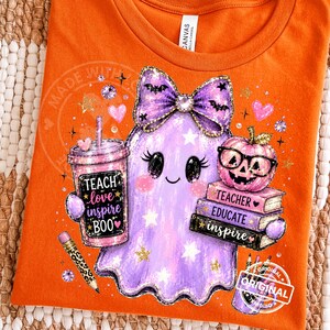 May include: An orange t-shirt featuring a graphic of a purple ghost wearing a bow, holding a tumbler with the text 'TEACH love inspire BOO', a stack of books labeled 'TEACHER', 'EDUCATE', 'inspire', a pumpkin with glasses, and a leopard print pencil.