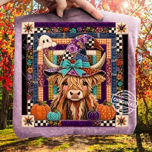 May include: A lavender sweatshirt featuring a central quilt-style graphic of a Highland cow wearing a purple floral witch hat with a teal bow. The design includes a small ghost, orange and teal pumpkins, and a decorative border of floral patterns.