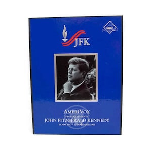 Puede incluir: Una caja azul con un retrato de John F. Kennedy. La caja tiene el texto "JFK" en rojo y blanco, junto con las palabras "AmeriVox Presents John Fitzgerald Kennedy" y sus fechas de nacimiento y defunción.