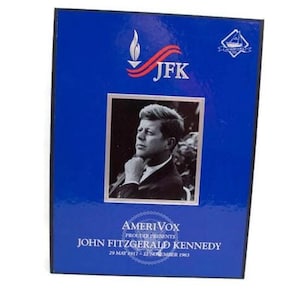 Puede incluir: Una caja azul con un retrato en blanco y negro de John F. Kennedy. La caja tiene el texto "JFK" con un diseño de antorcha y cinta. Debajo del retrato está el texto "AmeriVox Presents John Fitzgerald Kennedy 29 de mayo de 1917 - 22 de noviembre de 1963."