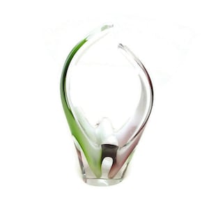 May include: A clear glass vase with a unique, abstract design. The vase features a curved, open shape with green and maroon accents. The base is rectangular, and the overall aesthetic is modern and artistic.