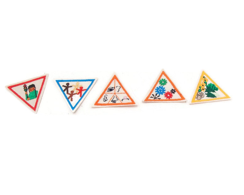 May include: Five triangular patches with embroidered designs. The patches feature images of a person with a traffic light, stick figures, symbols of the senses, gears, and plants. Each patch has a white background and a colored border.