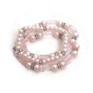 May include: Three-strand bracelet featuring faux pearls and pink rectangular beads. The bracelet is accented with small, sparkling rhinestones. The jewelry is set against a white background.