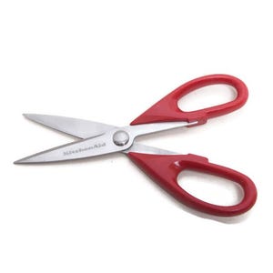 May include: KitchenAid kitchen shears featuring sharp stainless steel blades and bright red plastic handles. The brand name KitchenAid is clearly engraved on one of the metal blades near the central pivot point of the scissors.