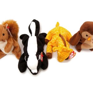 May include: Four plush animal toys: a brown squirrel, a black and white skunk, a yellow giraffe, and a brown owl. Each toy has a tag attached. The toys are on a white background.