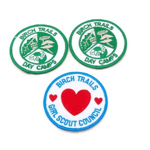 May include: Three circular patches. Two green and white patches read "BIRCH TRAILS DAY CAMPS". The third patch is blue and white with a red heart and reads "GIRL SCOUT COUNCIL".