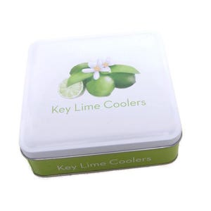 May include: A square tin with a white lid featuring a key lime design and the text "Key Lime Coolers." The tin has a green base and a silver rim. The design includes a key lime slice, whole limes, and a white flower.
