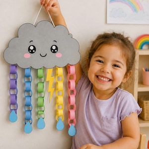Può includere: Una sagoma di nuvola in carta grigia con un viso sorridente, guance rosa e grandi occhi neri. Cinque catene di carta colorata pendono dal basso in viola, blu, verde, giallo e rosa, ognuna terminante con una goccia di pioggia in carta blu.