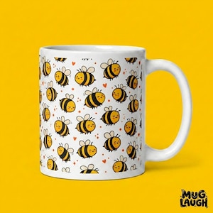 May include: White ceramic mug with a repeating pattern of cartoon bees in yellow and black, with small red hearts. The mug has a white handle and the words "Mug Laugh" in the bottom right corner.