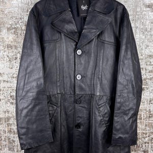 May include: A white ceramic mug with a black handle and the text "But First, Coffee" in a handwritten style. The mug is on a white surface. The mug is approximately 4 inches tall.