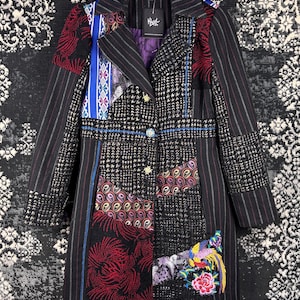 May include: A patchwork coat with a variety of patterns and textures. The coat features black and white houndstooth, striped, and floral fabrics. It has a notched collar, button closure, and a colorful embroidered bird detail.