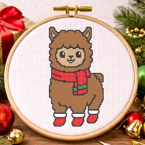 May include: A cross-stitch embroidery hoop featuring a brown llama wearing a red scarf and boots. The llama is surrounded by Christmas ornaments, pine needles, and a wrapped gift box. The hoop is made of wood.