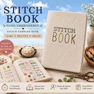 May include: A beige fabric-covered stitch book with the words STITCH BOOK embroidered in green. The book is displayed alongside an open sampler book showing various embroidery stitches, a pincushion, a basket of embroidery floss, and scissors.