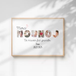 Peut inclure: Un cadre en bois clair contenant une impression avec le mot "NOUNOU" formé de photos de bébé. Le cadre contient également le texte "Merci" et "De m'avoir fait grandir Elena 2022/2025" en écriture noire.